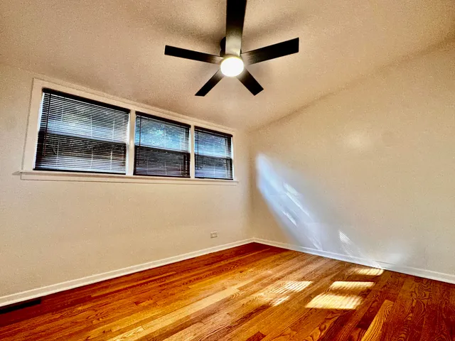 a view of empty room with wooden floor and fan