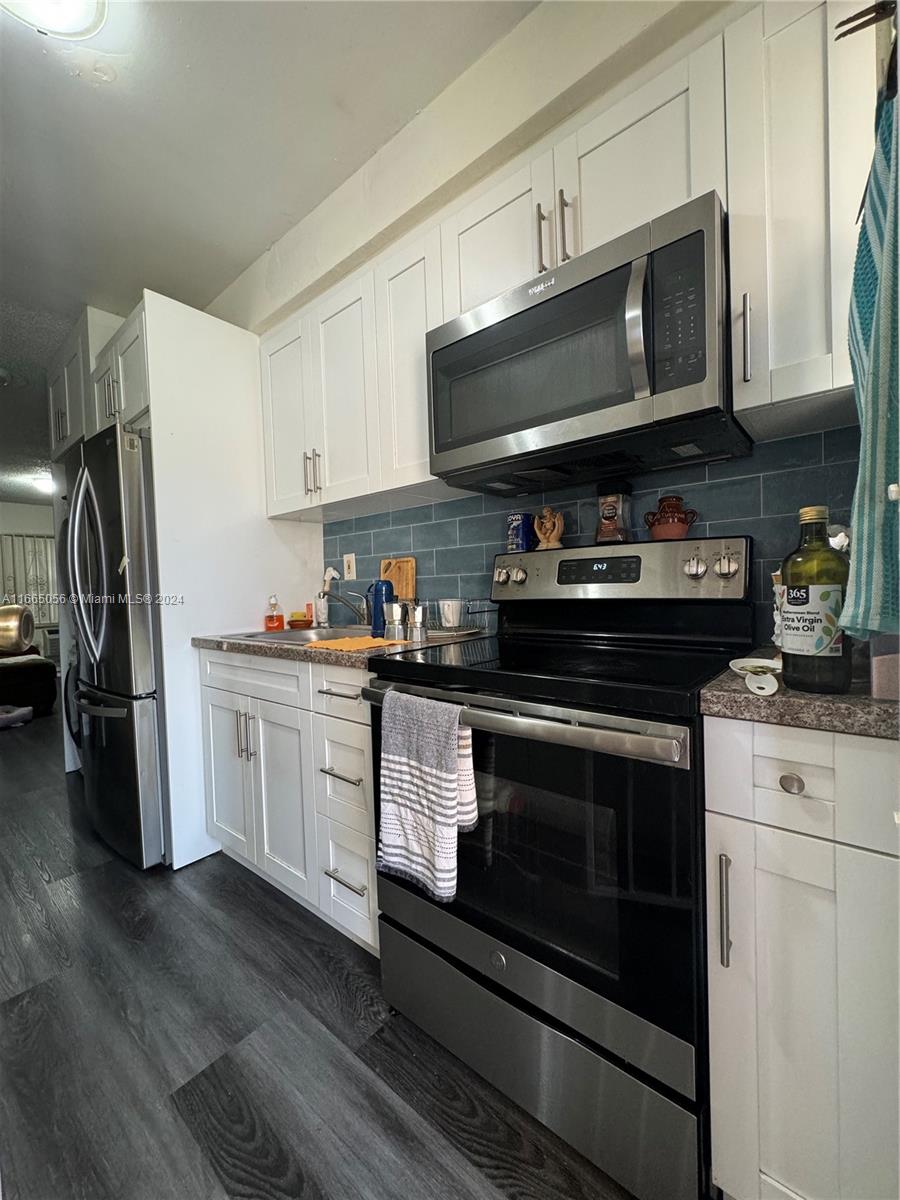 3551 Southwest 10th Street, Unit 8A Miami, FL 33135 - Photo 3 of 10 a kitchen with stainless steel appliances granite countertop a stove a refrigerator and a microwave