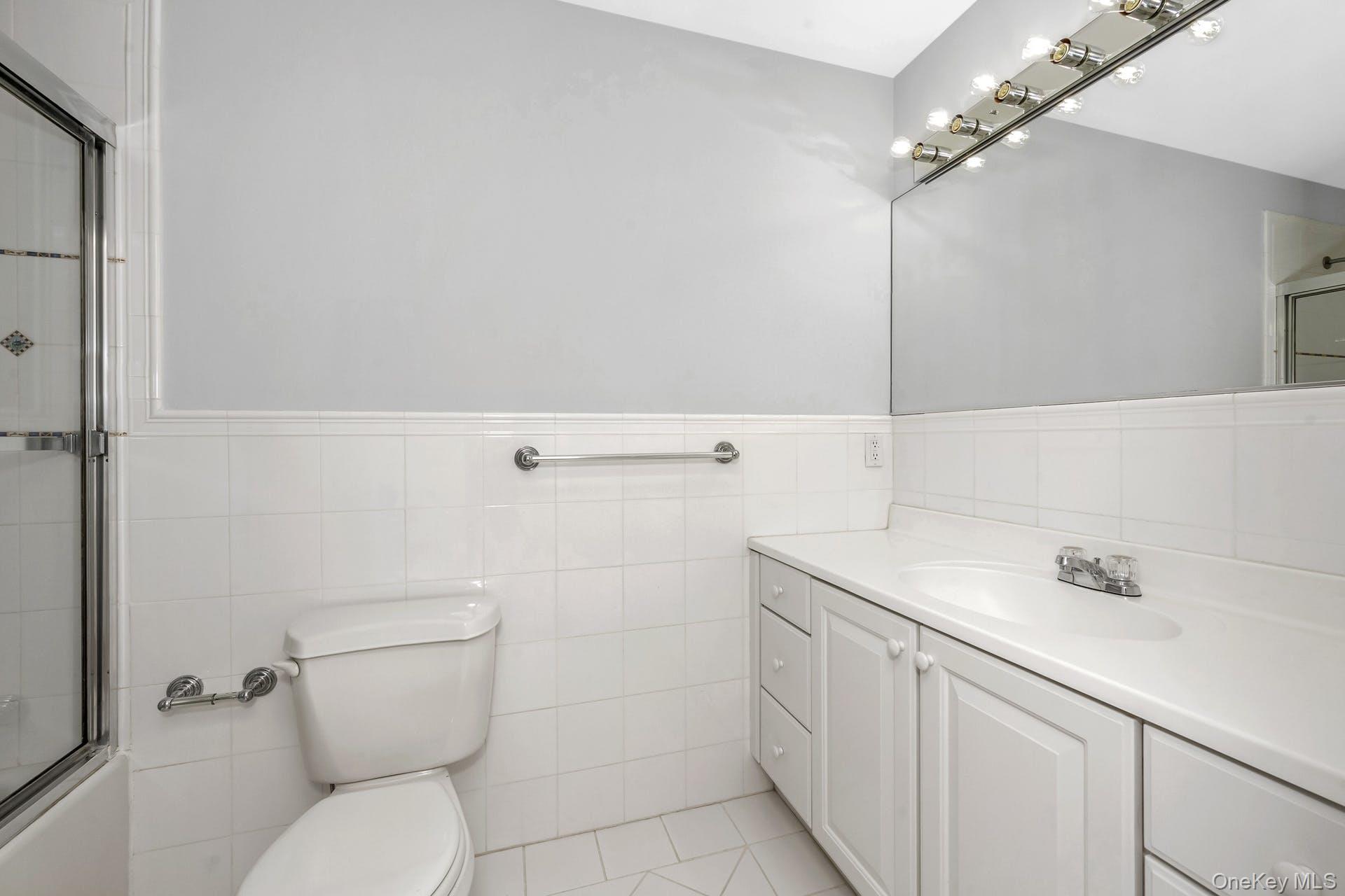 69 Ellsworth Avenue Harrison, NY 10528 - Photo 13 of 28 Full bath featuring vanity, tile walls, wainscoting, and combined bath / shower with glass door