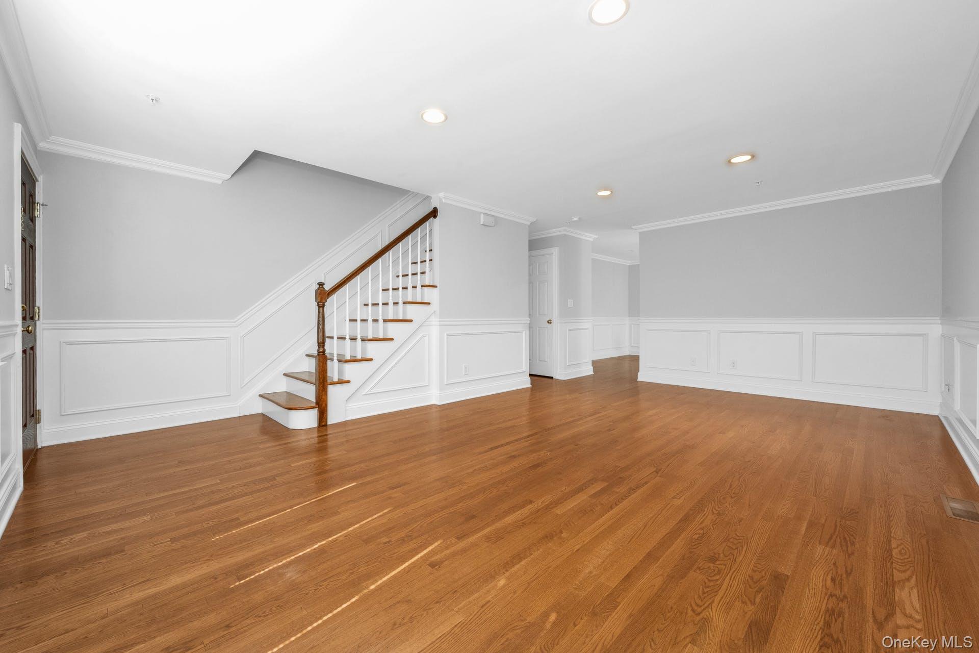 69 Ellsworth Avenue Harrison, NY 10528 - Photo 3 of 28 Unfurnished living room with stairway, a wainscoted wall, a decorative wall, recessed lighting, and wood finished floors