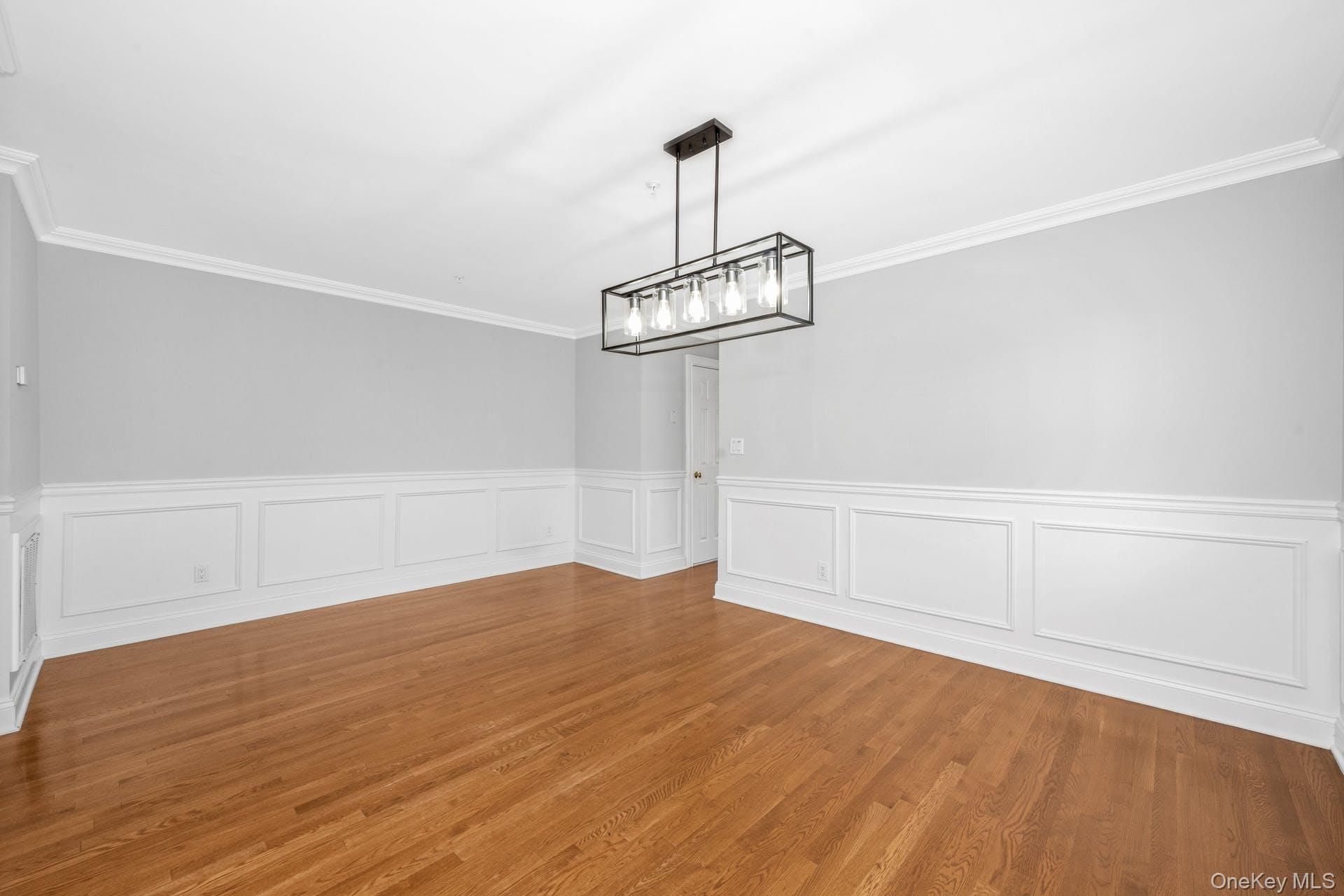 69 Ellsworth Avenue Harrison, NY 10528 - Photo 5 of 28 Unfurnished dining area featuring crown molding, a wainscoted wall, and wood finished floors