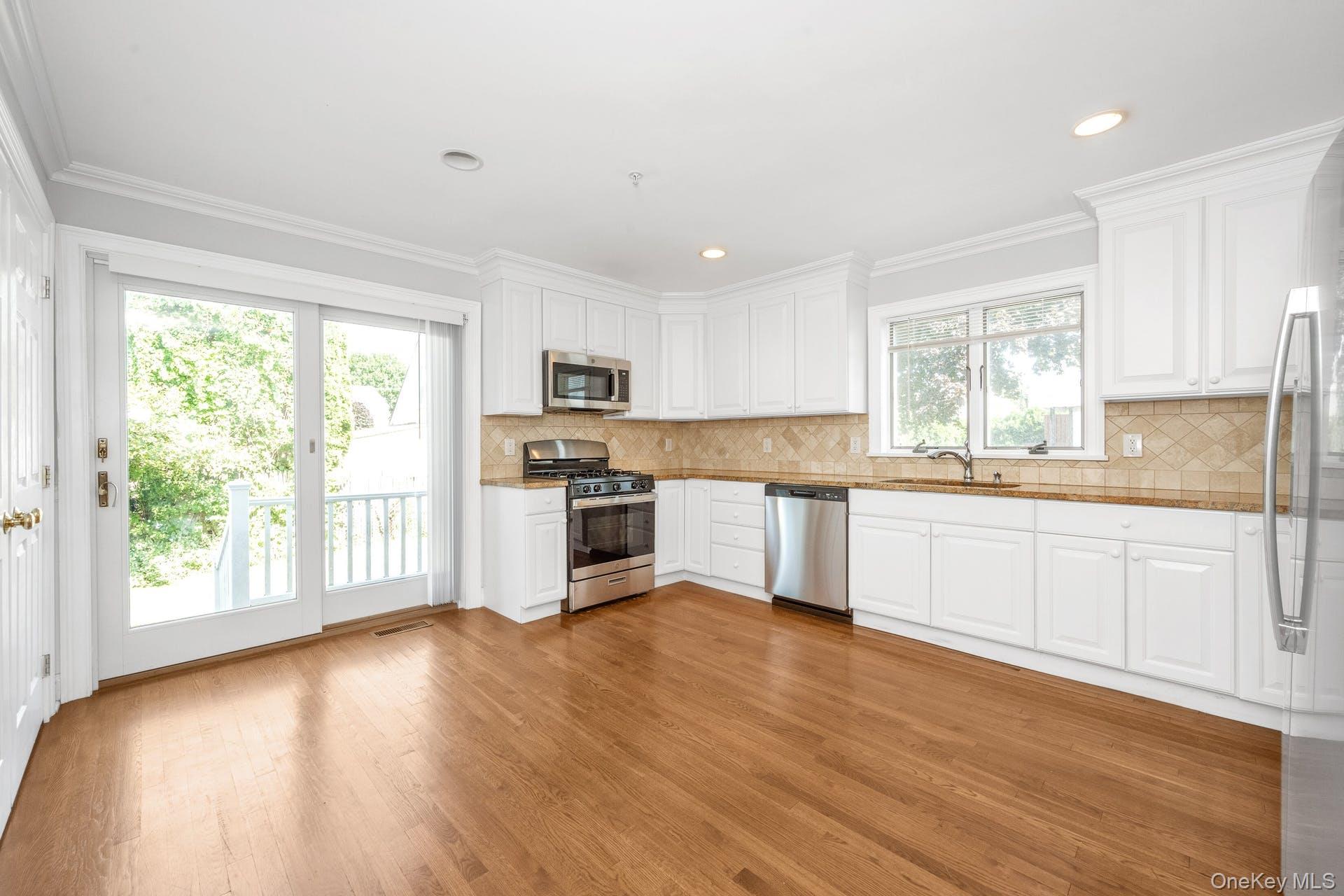 69 Ellsworth Avenue Harrison, NY 10528 - Photo 6 of 28 Kitchen featuring appliances with stainless steel finishes, light wood-style flooring, white cabinetry, ornamental molding, and recessed lighting