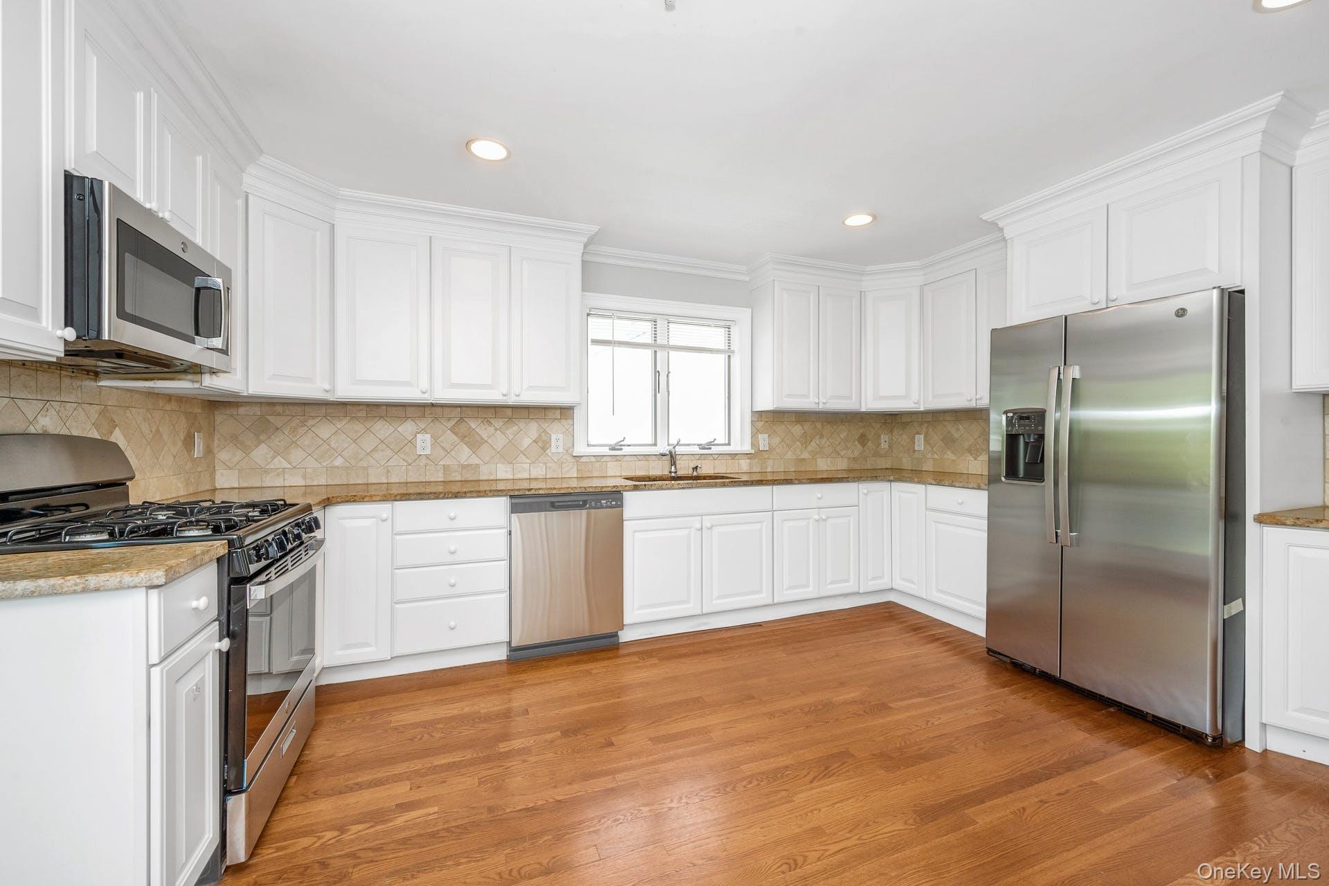 69 Ellsworth Avenue Harrison, NY 10528 - Photo 8 of 28 Kitchen with appliances with stainless steel finishes, light wood finished floors, white cabinetry, decorative backsplash, and recessed lighting