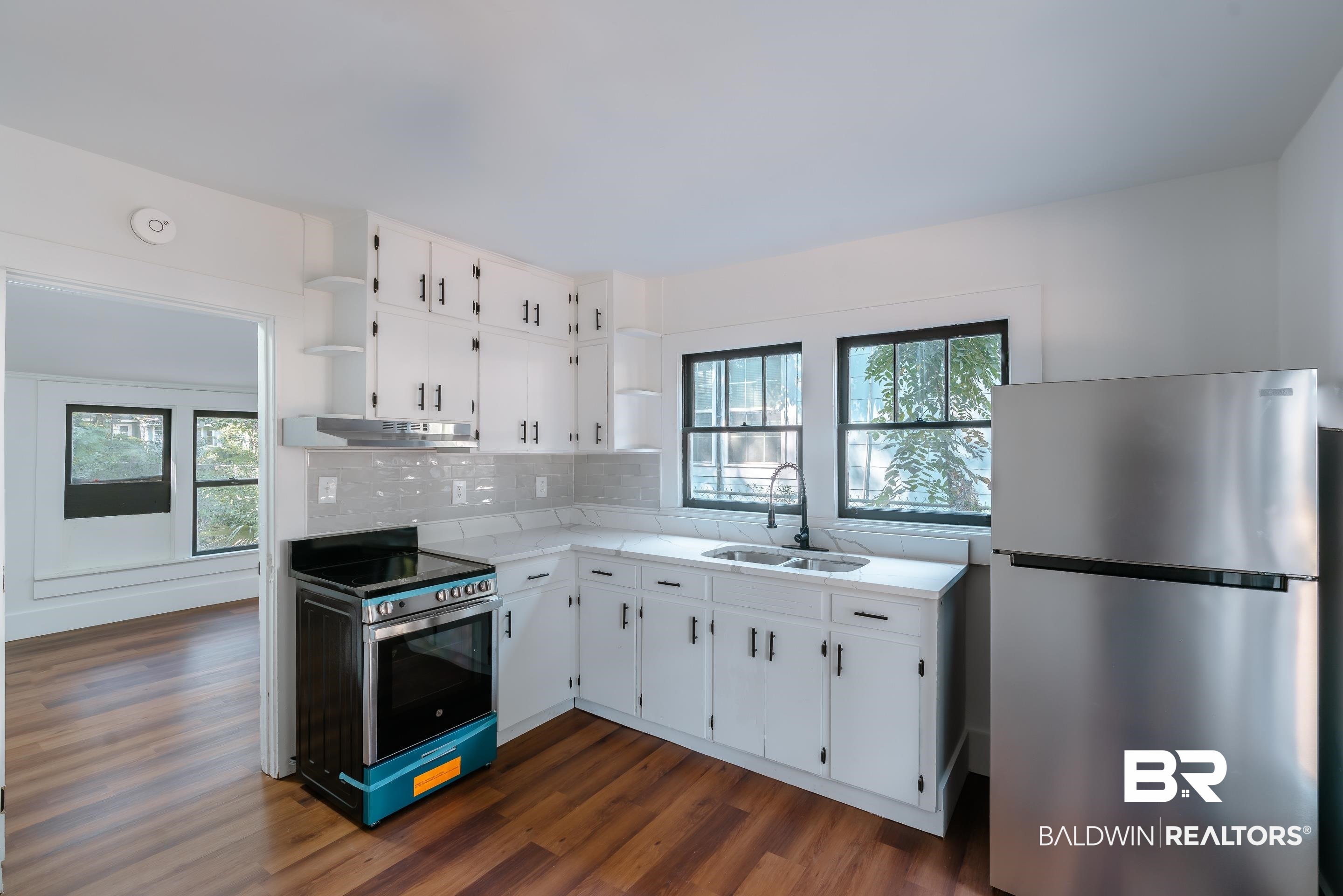 166 Crenshaw Street Mobile, AL 36606 - Photo 3 of 24 Kitchen featuring dark wood-type flooring, stainless steel appliances, sink, white cabinetry, and tasteful backsplash
