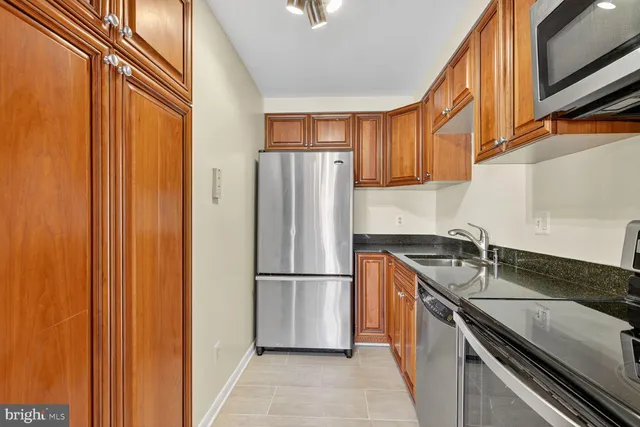 a kitchen with granite countertop stainless steel appliances a refrigerator and a sink
