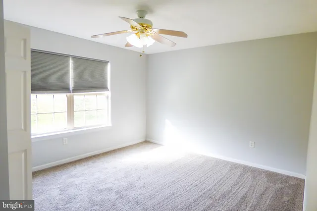 an empty room with a window and a ceiling fan