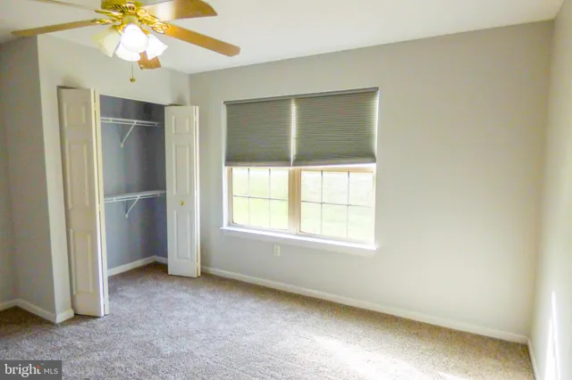 an empty room with a window and a fan