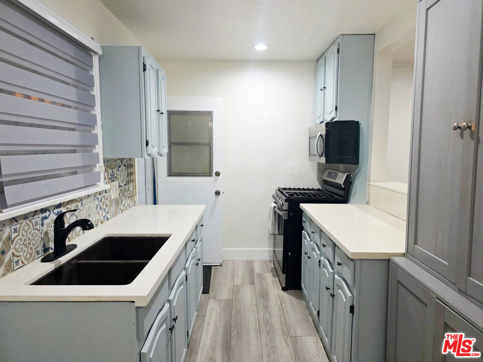 1111 North Spring Avenue Compton, CA 90221 - Photo 18 of 28 a kitchen with a sink a stove and a refrigerator