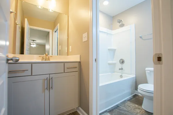 a bathroom with a bathtub shower sink mirror vanity and toilet