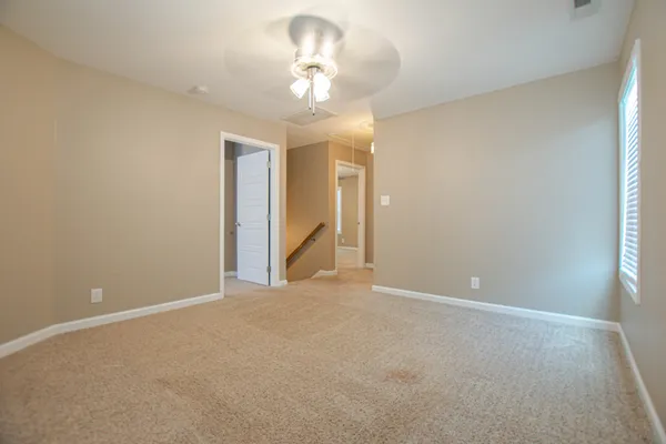 a view of an empty room with a chandelier fan