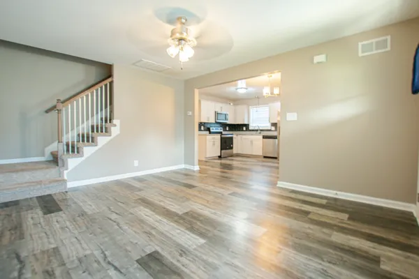 a view of empty room with wooden floor and kitchen view