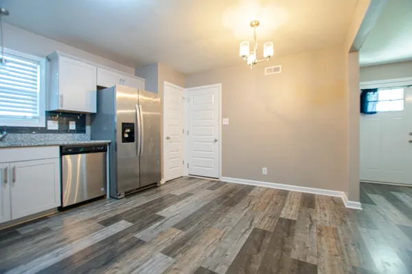 a view of a kitchen with a sink and dishwasher with wooden floor