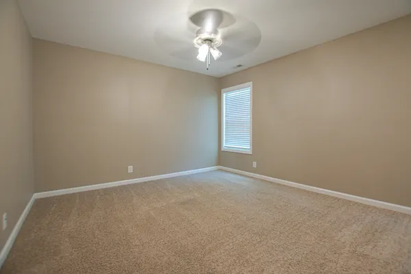 a view of an empty room and a chandelier fan