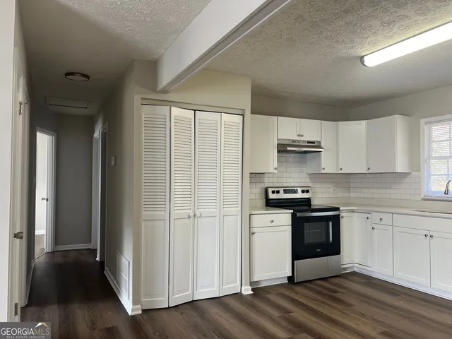 a kitchen with stainless steel appliances granite countertop a stove a sink and white cabinets