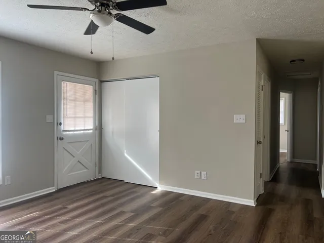 an empty room with wooden floor fan and windows
