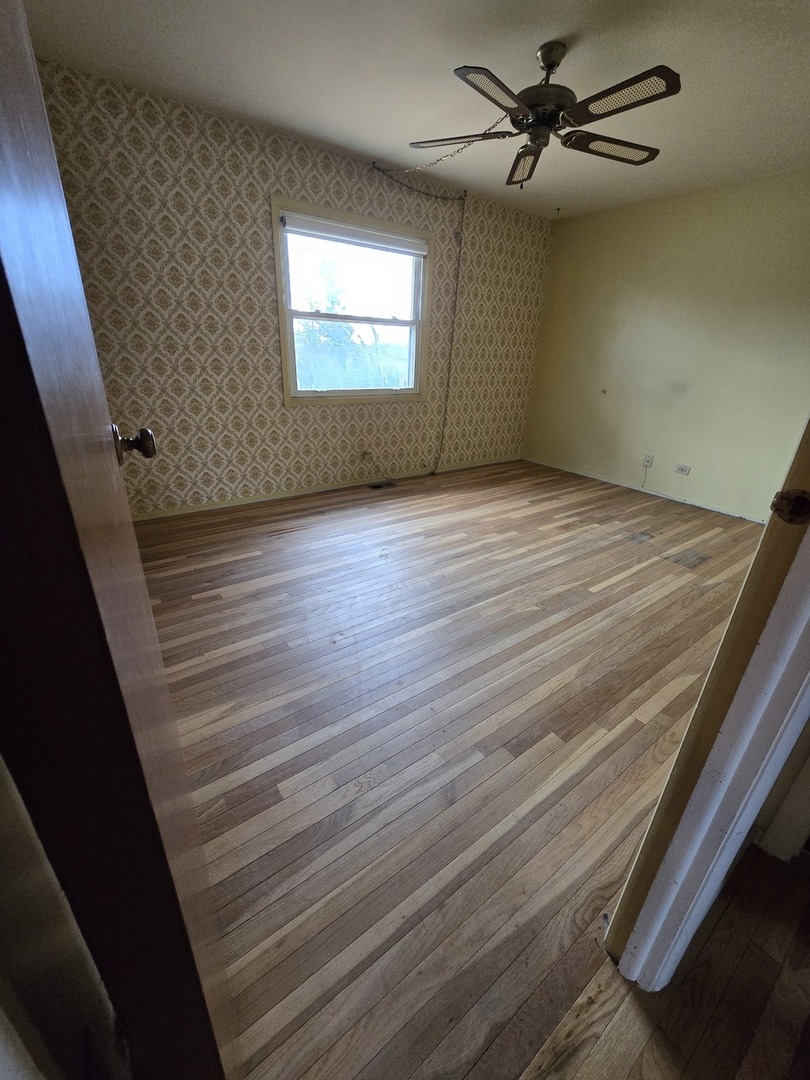 2075 Greenfield Road Hoffman Estates, IL 60169 - Photo 10 of 23 an empty room with wooden floor fan and windows