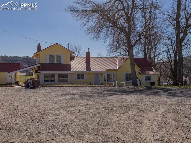 a front view of a house with a dirt yard and a large tree