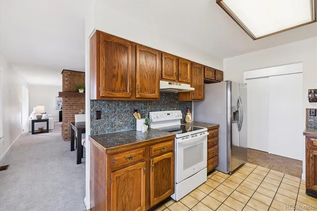 a kitchen with stainless steel appliances granite countertop a stove a sink and a refrigerator