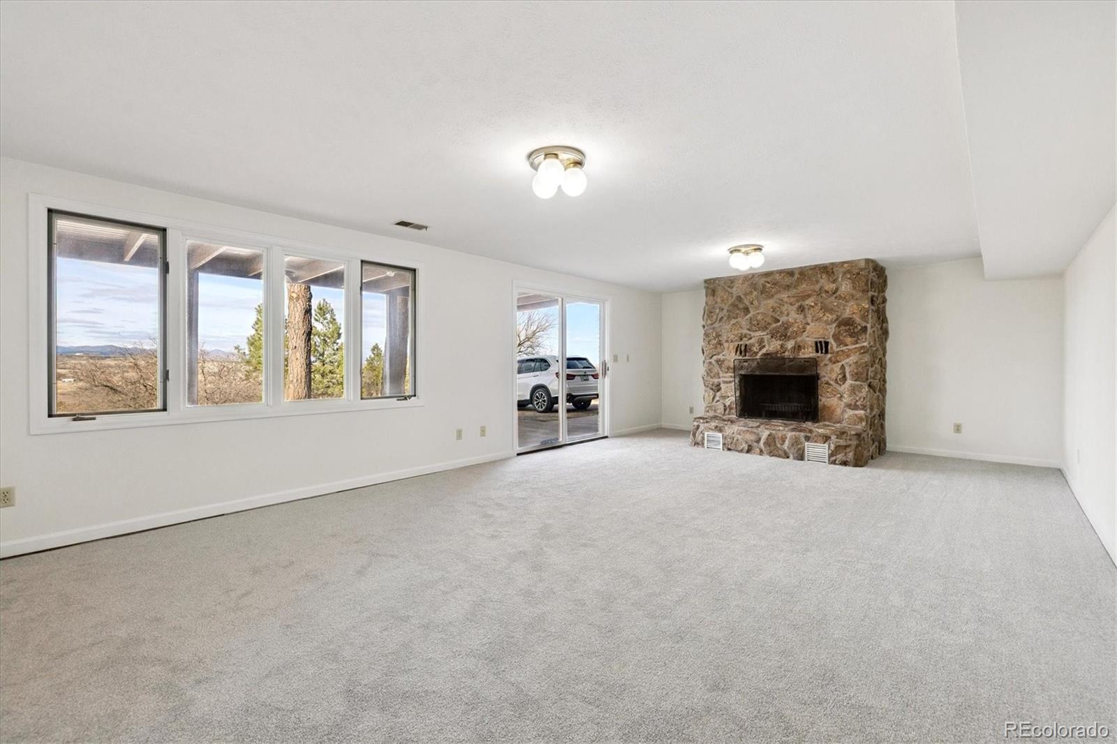1482 North Perry Park Road Sedalia, CO 80135 - Photo 44 of 50 an empty room with a fireplace and windows