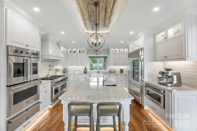 a kitchen with stainless steel appliances granite countertop a stove top oven a sink dishwasher a dining table and chairs with wooden floor