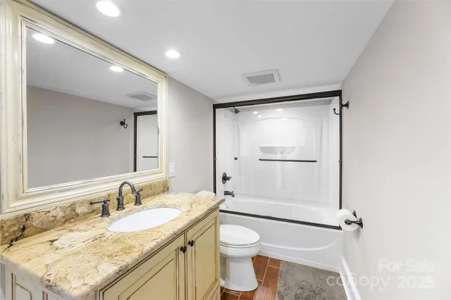 a bathroom with a granite countertop sink mirror vanity and toilet