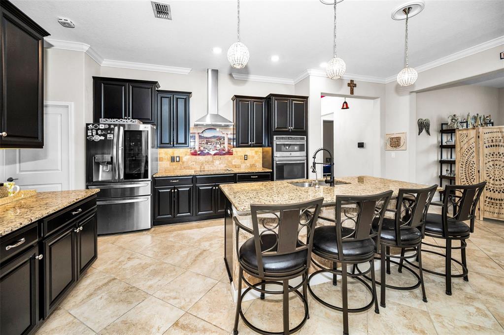 16833 Banner Shell Place Wimauma, FL 33598 - Photo 11 of 55 a kitchen with stainless steel appliances kitchen island granite countertop a dining table chairs refrigerator and microwave