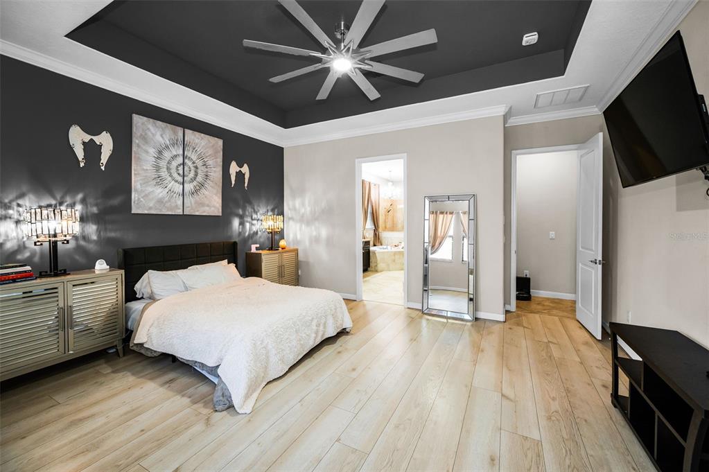 16833 Banner Shell Place Wimauma, FL 33598 - Photo 21 of 55 a spacious bedroom with a bed and a flat tv screen on dresser