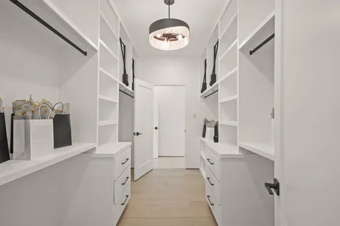 a hallway with white cabinets and chandelier