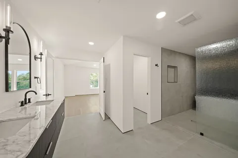 a bathroom with a double vanity sink and mirror with bathtub