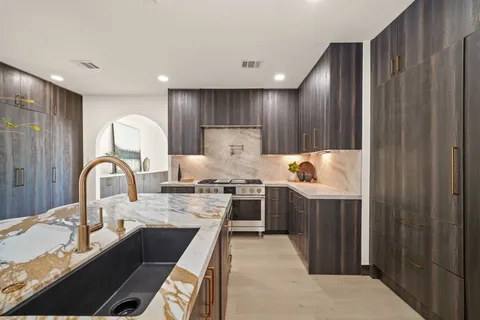 a kitchen with kitchen island granite countertop a stove and a sink
