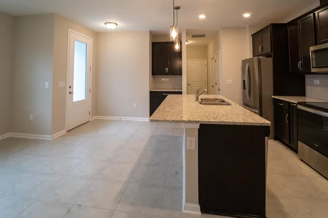 a large kitchen with a refrigerator a sink and a stove top oven
