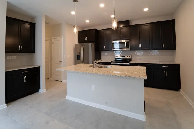 a kitchen with stainless steel appliances kitchen island granite countertop a stove a sink and a refrigerator