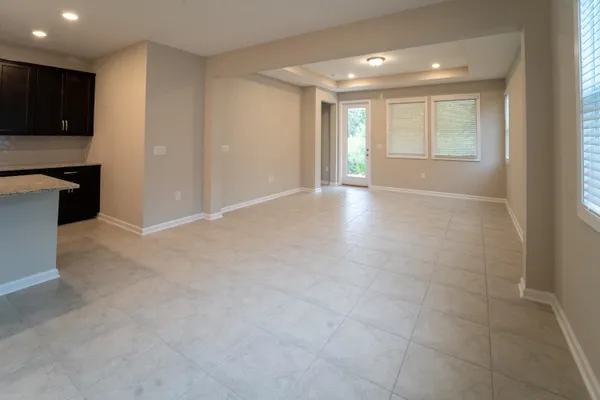 a view of an empty room with kitchen and a window