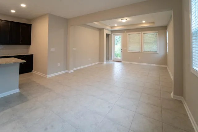 a view of an empty room with kitchen and a window