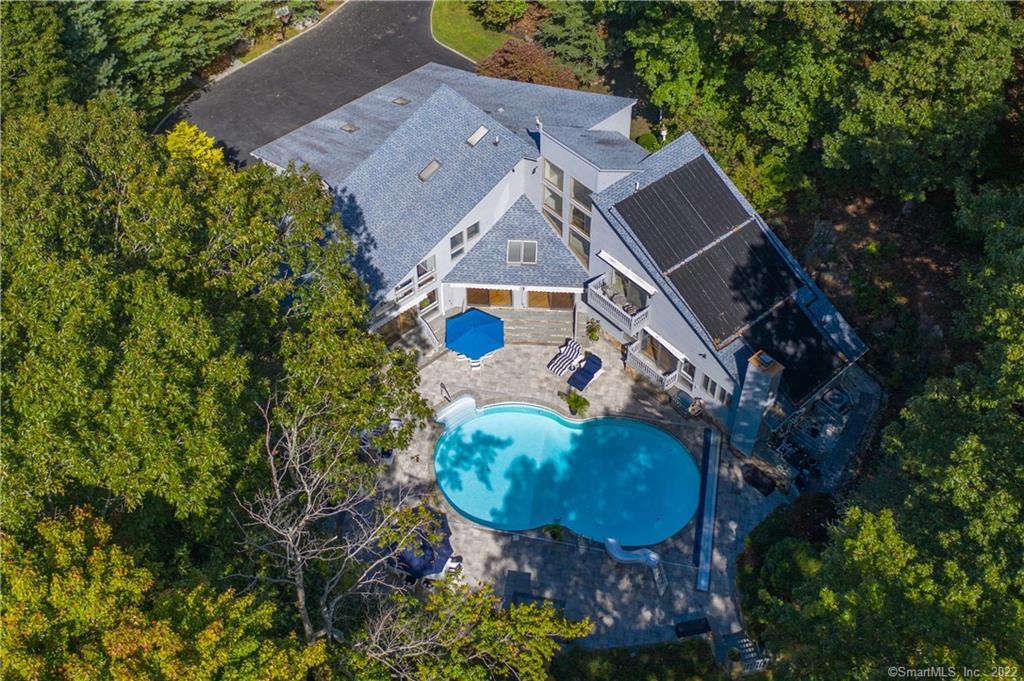 an aerial view of a house with a swimming pool and large trees