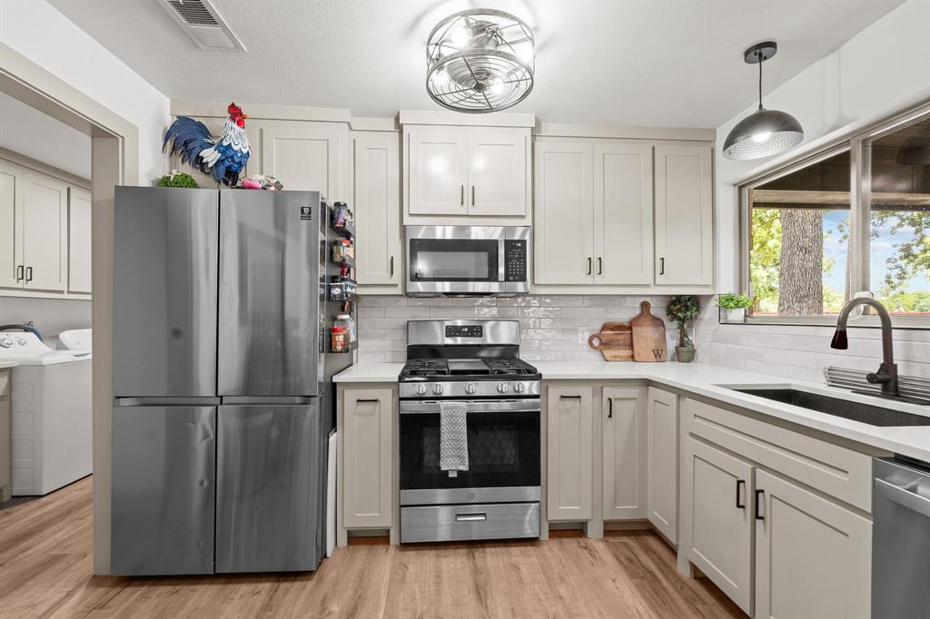 220 South Ash Street Springtown, TX 76082 - Photo 23 of 40 a kitchen with a stove a refrigerator and a sink