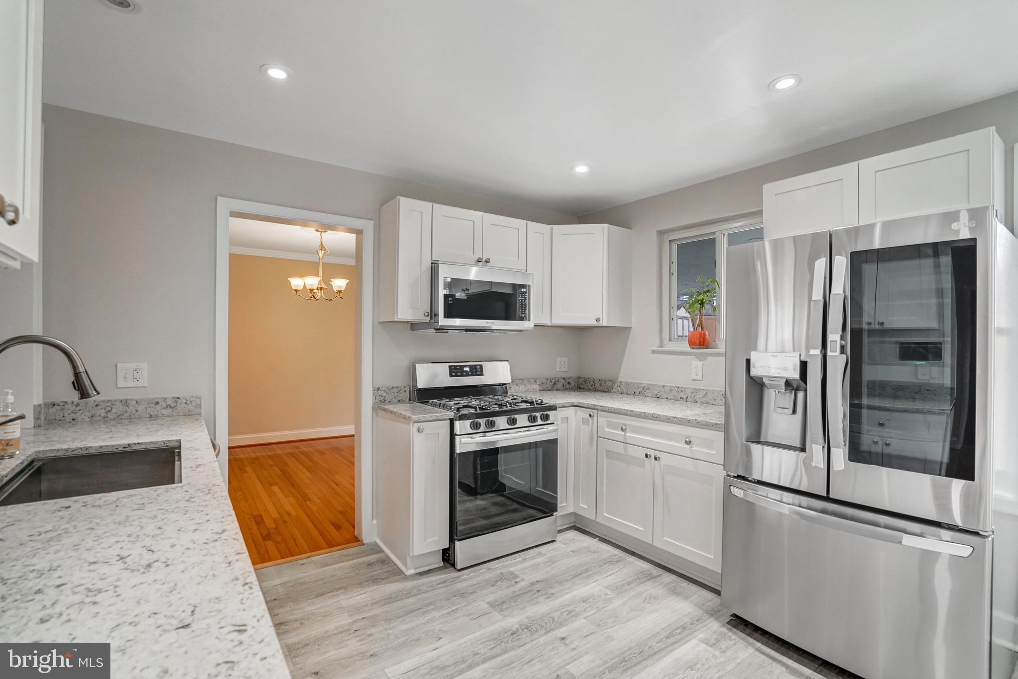 8941 Burke Lake Road Springfield, VA 22151 - Photo 6 of 34 a kitchen with stainless steel appliances granite countertop a refrigerator a stove and a sink with wooden floor