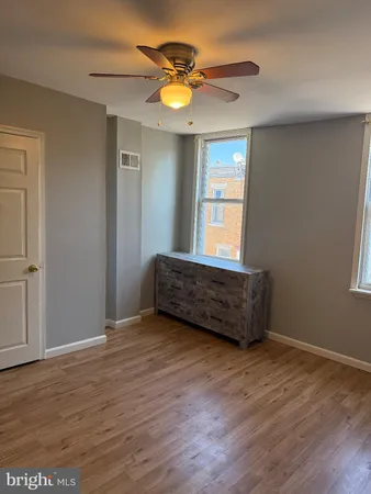an empty room with wooden floor windows and ceiling fan