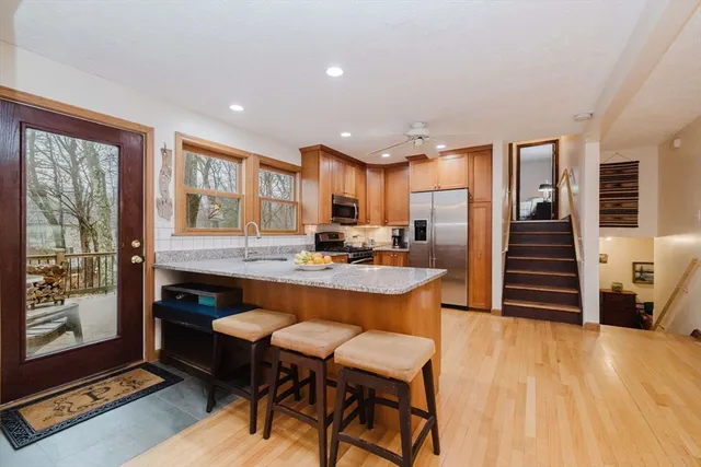 a kitchen with stainless steel appliances granite countertop a stove top oven a sink dishwasher a dining table and chairs with wooden floor