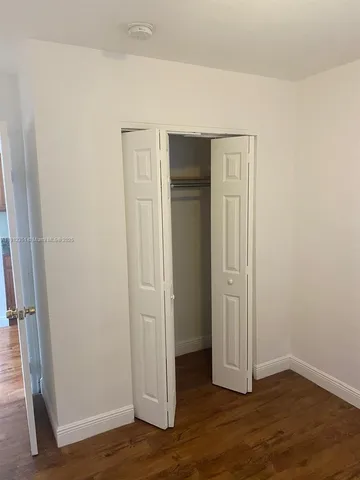 an empty room with wooden floor and closet