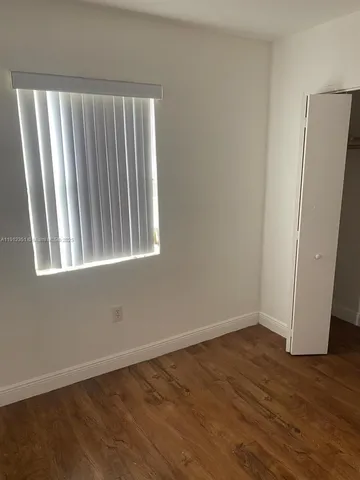 an empty room with wooden floor and a window