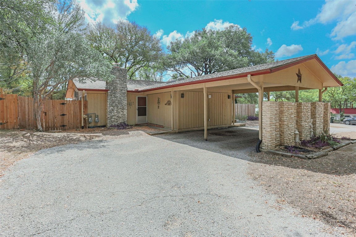a backyard of a house with large tree and wooden fence