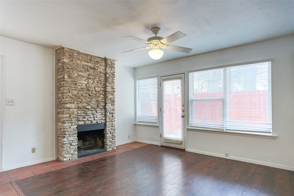 1003 Beaver Trail, Unit A Austin, TX 78746 - Photo 3 of 15 an empty room with windows chandelier and fireplace