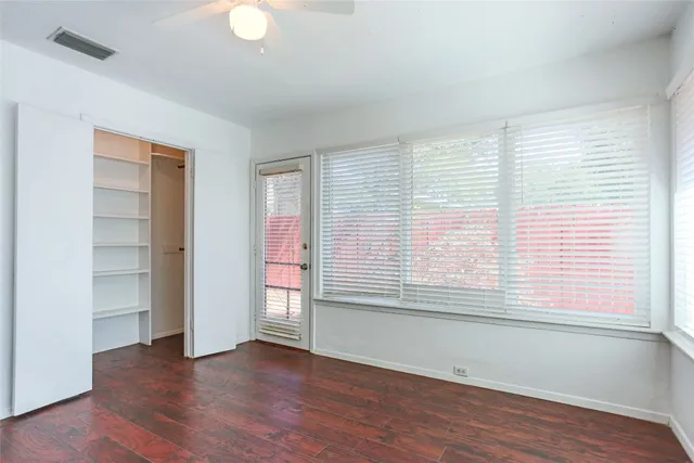 a view of an empty room with a window and wooden floor