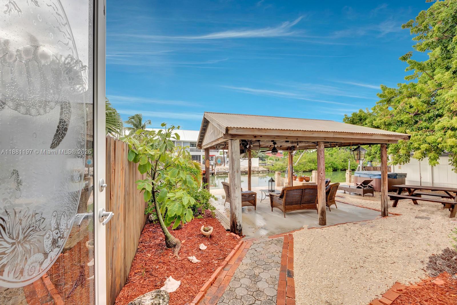 308 Sombrero Beach Road Marathon, FL 33050 - Photo 30 of 43 a view of a patio with table and chairs potted plants with wooden floor and fence