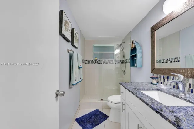 a bathroom with a granite countertop sink toilet and shower