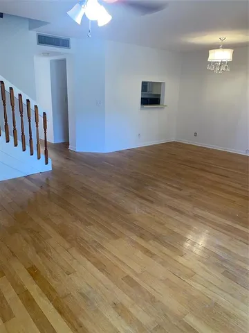 a view of a room with wooden floor and a ceiling fan