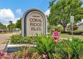a view of a sign board with flower plants and wooden fence