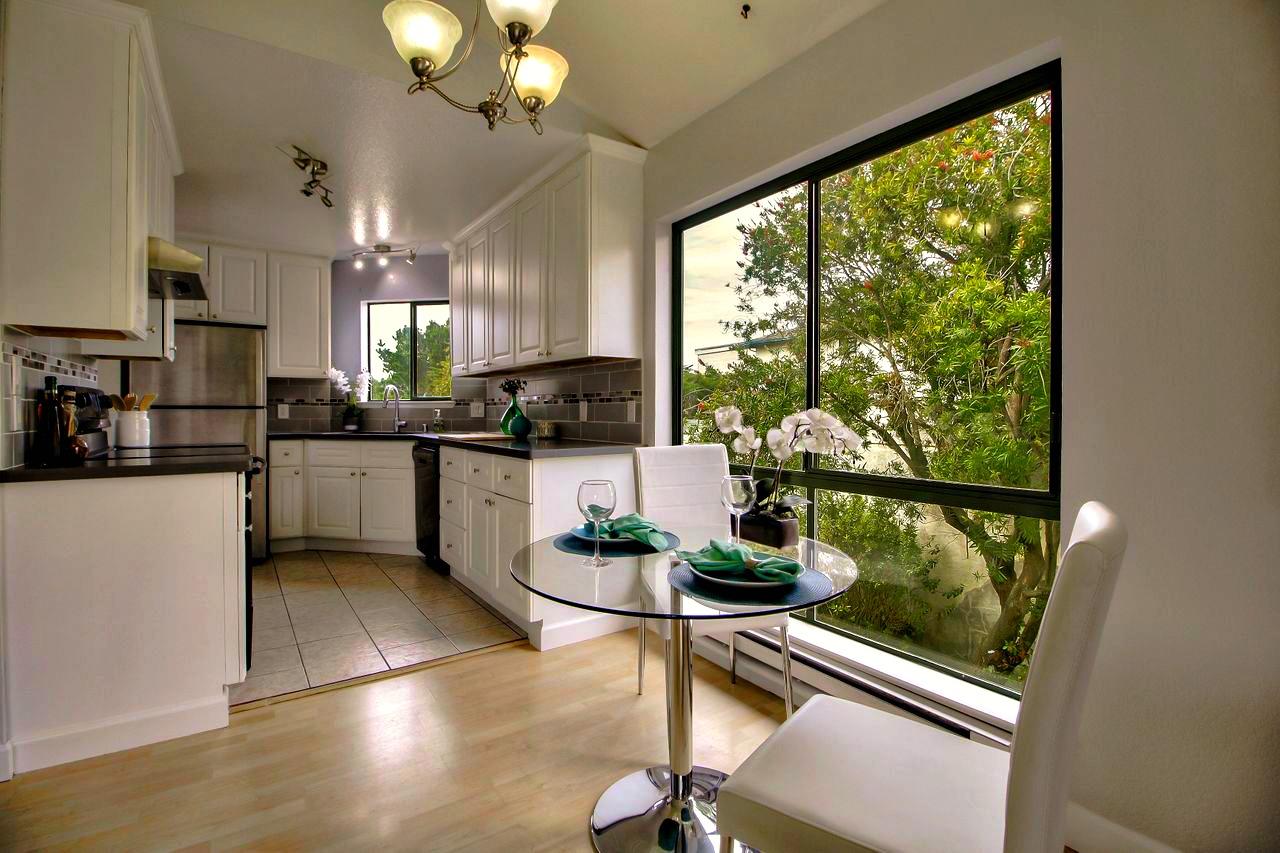 207 Monterey Road, Unit 7 Pacifica, CA 94044 - Photo 6 of 34 a kitchen with stainless steel appliances kitchen island granite countertop a stove a refrigerator a sink a dining table and chairs next to a window
