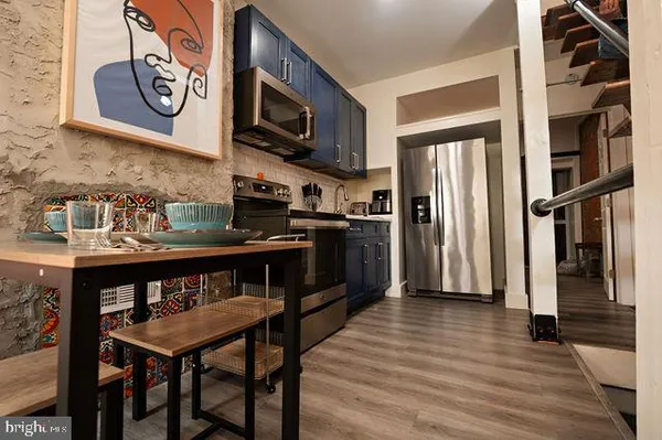 a kitchen with stainless steel appliances granite countertop a refrigerator a stove and a wooden floor